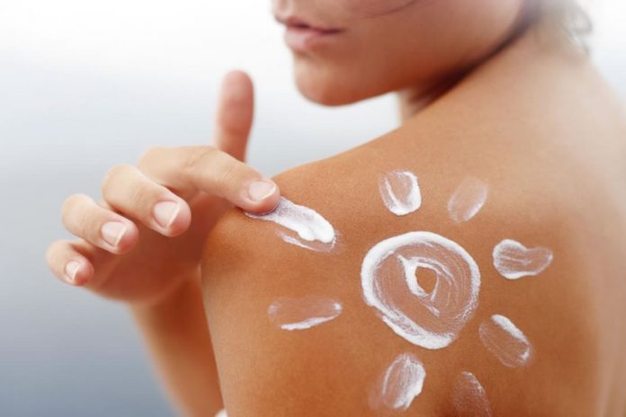 woman rubbing sun tan lotion